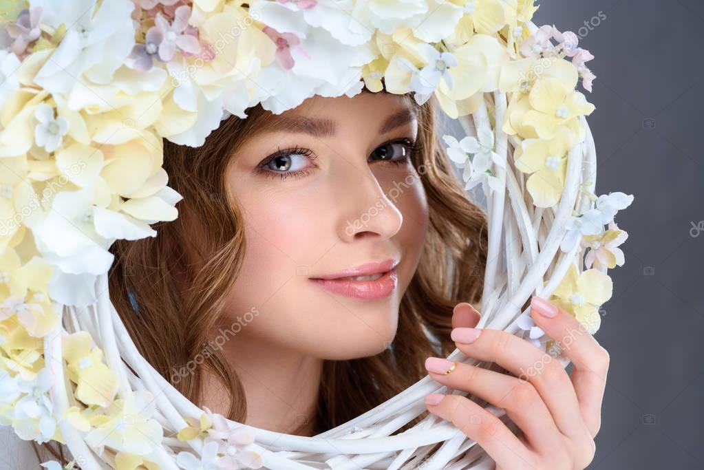 attractive young woman behind floral wreath