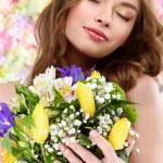 花の花束を保持している美しい若い女性のクローズ アップの肖像画
