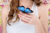 Schnappschuss einer Frau mit einem schönen blauen Schmetterling auf der Hand