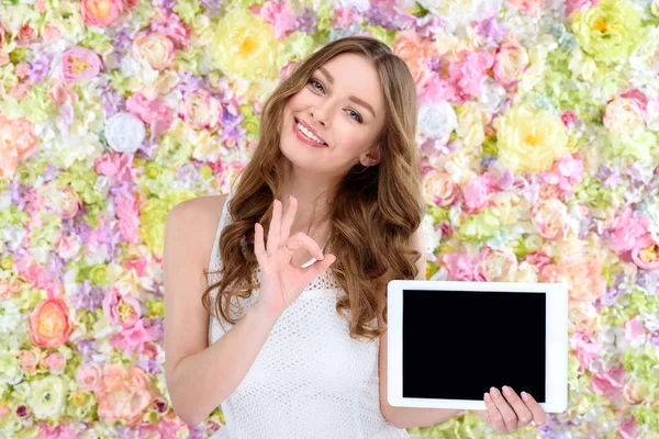 Bela Jovem Com Tablet Mostrando Sinal Fundo Floral — Fotografia de Stock