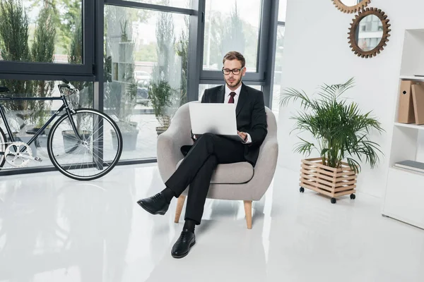 Uomo d'affari che lavora sul computer portatile mentre si siede ufficio — Foto stock