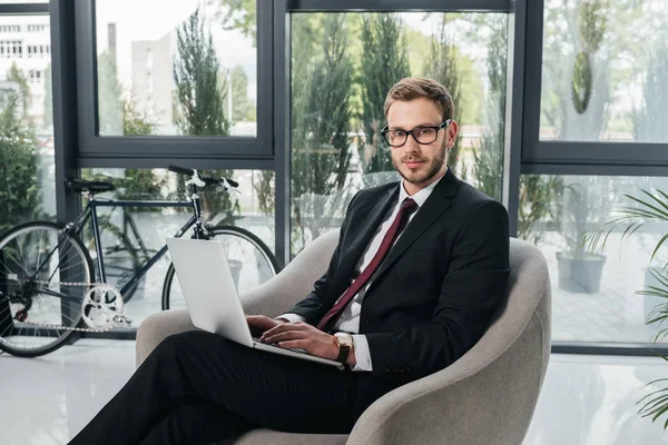 Businessman in suit working on laptop at office — Stock Photo