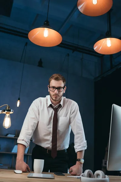 Geschäftsmann stützt sich im Büro auf Tisch — Stockfoto