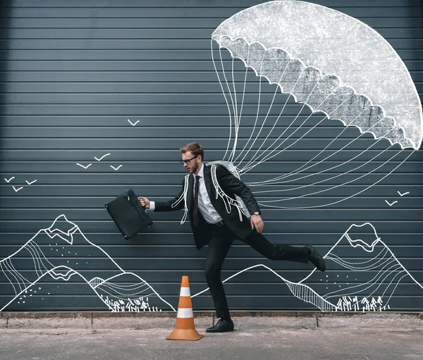 Uomo d'affari che corre con il paracadute — Foto stock