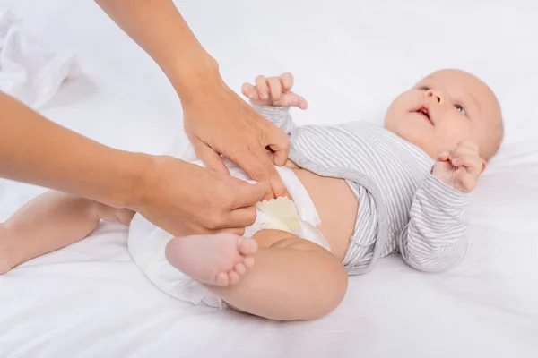 Madre cambiando pañales de bebé - foto de stock