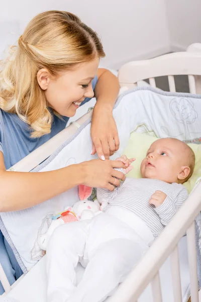 Mãe olhando para o bebê no berço — Fotografia de Stock
