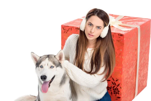 Husky cane e bella donna in inverno paraorecchie con grande regalo di Natale dietro, isolato su bianco — Foto stock