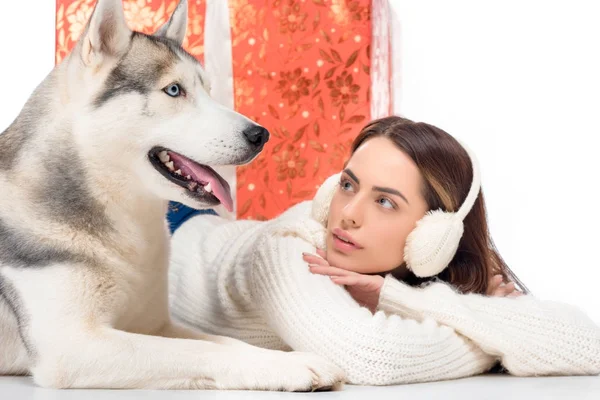 Cão husky e mulher bonita em earmuffs de inverno com grande presente de Natal atrás, isolado em branco — Fotografia de Stock