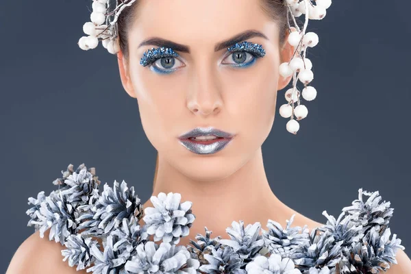 Retrato de menina bonita com acessório de cabelo, cones de pinho de natal, maquiagem de inverno e brilho, isolado em cinza — Fotografia de Stock