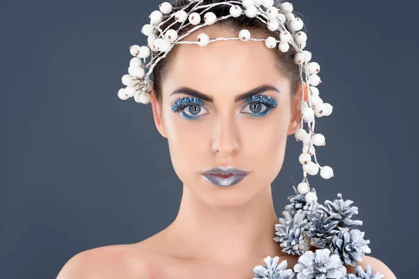 Retrato de mulher bonita com acessório de cabelo, cones de pinho de natal, maquiagem de inverno e glitter, isolado em cinza — Fotografia de Stock