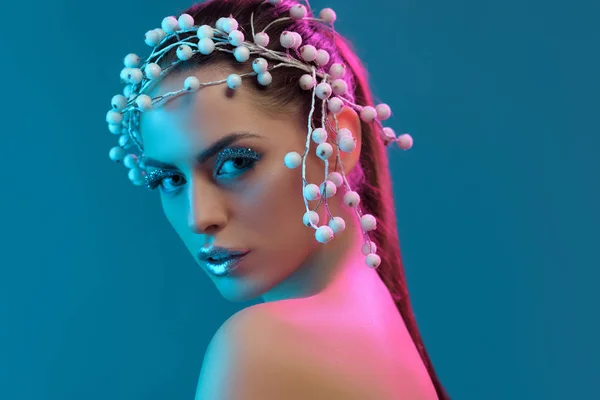 Ritratto di bella donna con accessorio per capelli, trucco invernale e glitter in posa per le riprese di moda, isolato su blu — Foto stock