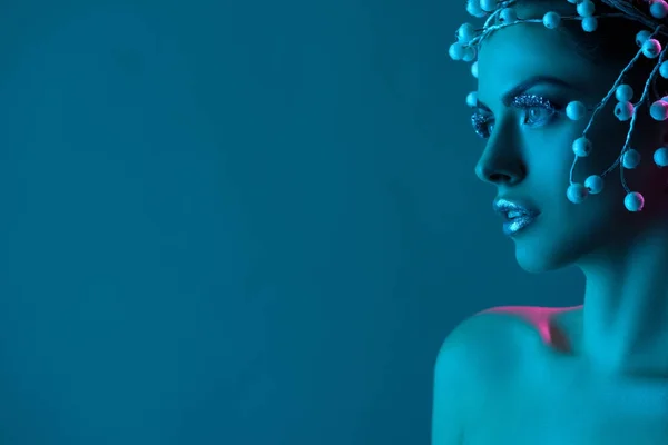 Schöne Frau mit Haar-Accessoire, Winter-Make-up und Glitzer posiert für Mode-Shooting, isoliert auf blau — Stockfoto