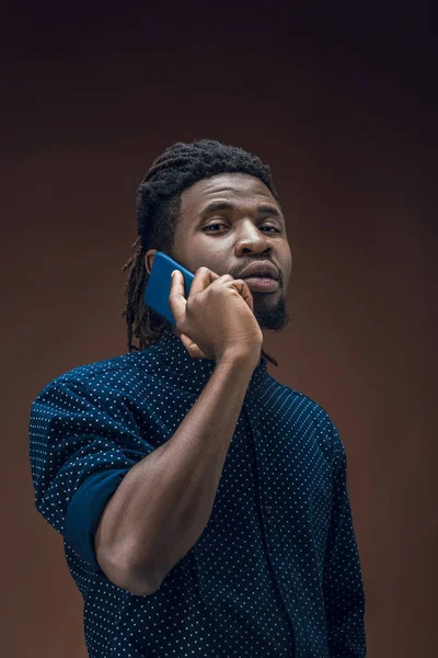 African american man talking by smartphone isolated on brown — Stock Photo