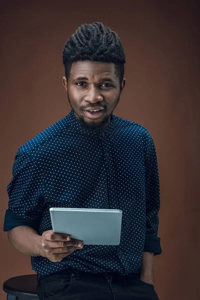 Homem americano africano segurando tablet isolado em marrom — Fotografia de Stock