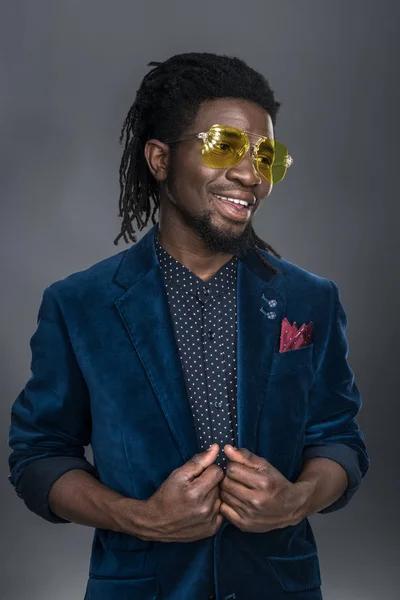 Smiling handsome african american man in yellow sunglasses looking away isolated on gray — Stock Photo