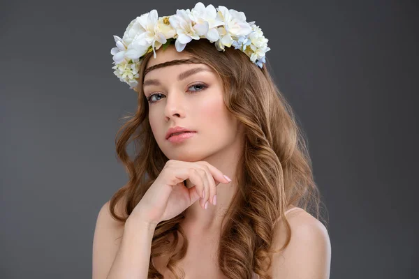 Приваблива молода жінка з кучерявим волоссям у квітковому вінку ізольована на сірому — стокове фото
