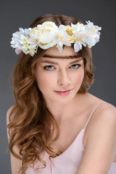 Красива молода жінка з кучерявим волоссям у квітковому вінку ізольована на сірому — стокове фото