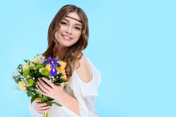 Счастливая молодая женщина с цветочным букетом изолированы на синий — стоковое фото