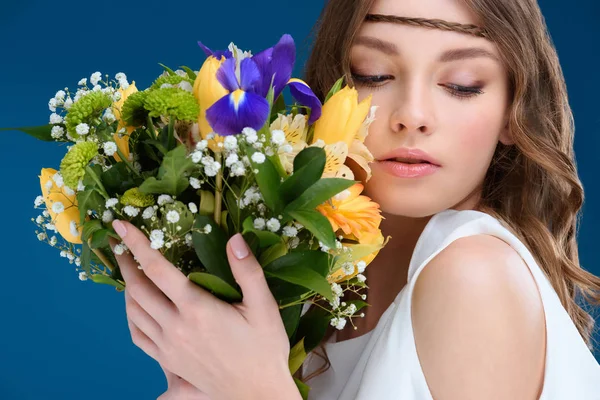 Bella giovane donna tenendo bouquet floreale isolato su blu — Foto stock