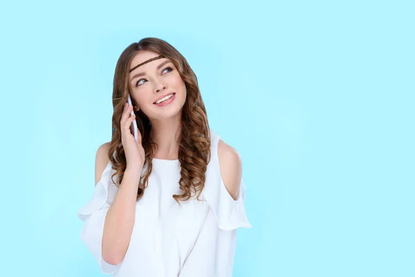Красивая молодая женщина разговаривает по телефону изолированы на синий — стоковое фото