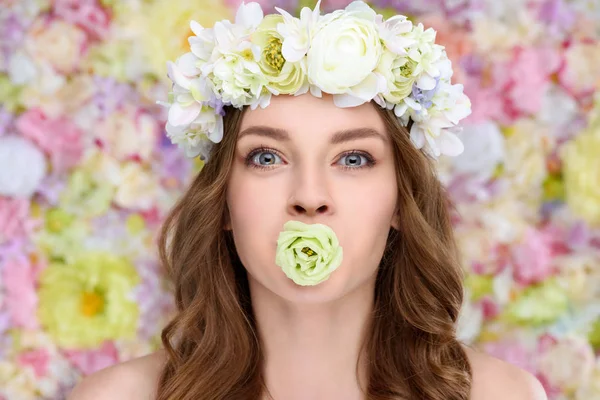 Junge Frau im Blumenkranz mit blühender Rosenknospe im Mund — Stockfoto