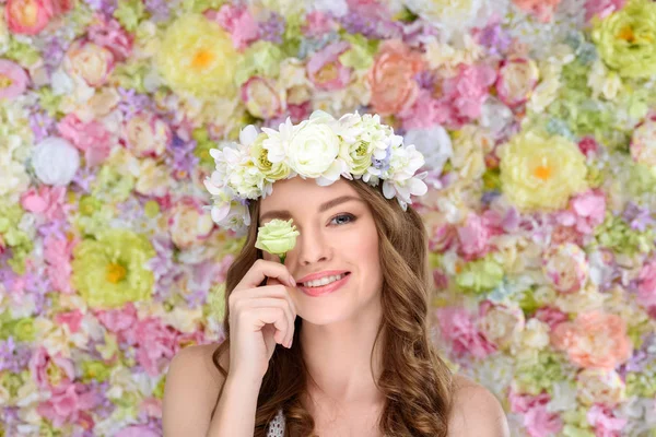 Счастливая молодая женщина в цветочном венке, покрывая один глаз цветущим бутоном роз — стоковое фото
