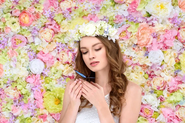Молодая женщина с вьющимися волосами в цветочном венке с бабочкой на руке — стоковое фото