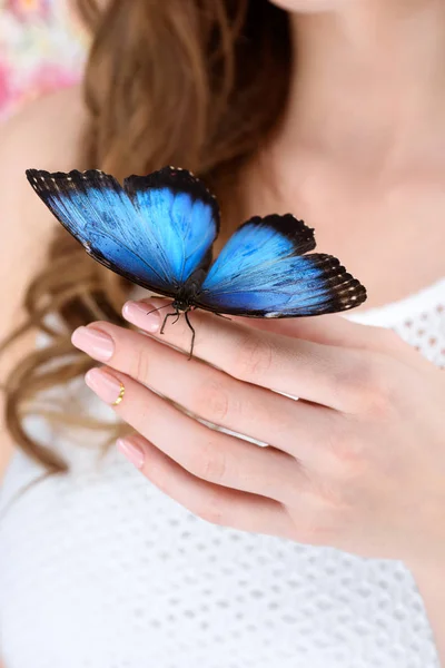 Cropped shot of woman with blue butterfly on hand — Stock Photo