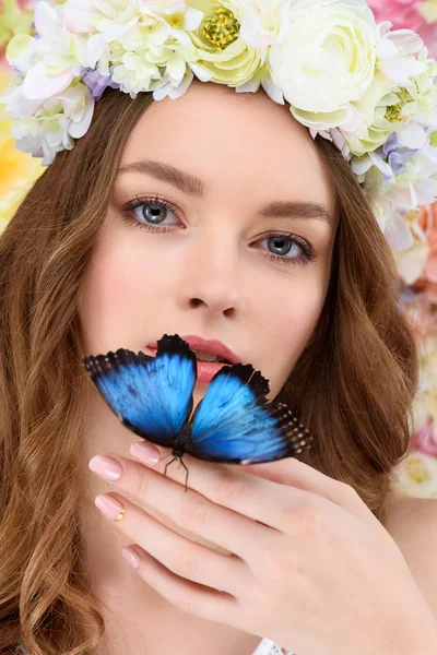 Retrato de cerca de la sensual joven en corona floral con mariposa en la mano - foto de stock