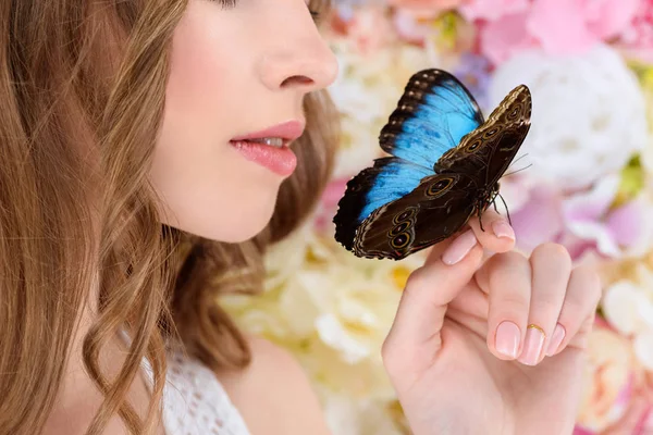 Tiro recortado de mujer joven con mariposa en la mano - foto de stock