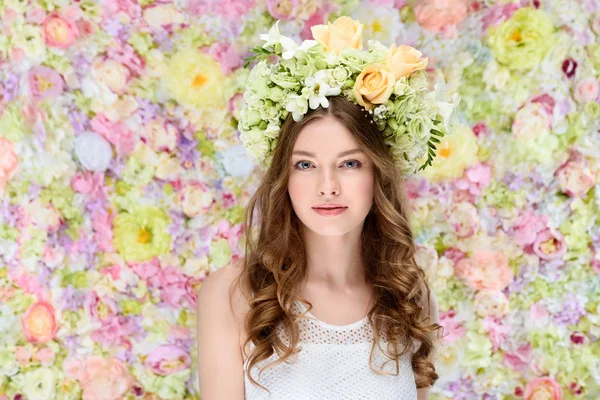 Attractive young woman in floral wreath on floral background — Stock Photo