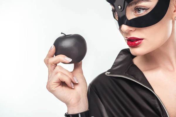 Seductive young woman in mask holding black apple isolated on white — Stock Photo