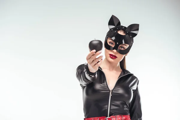 Jeune femme séduisante en masque tenant pomme noire isolée sur blanc — Photo de stock