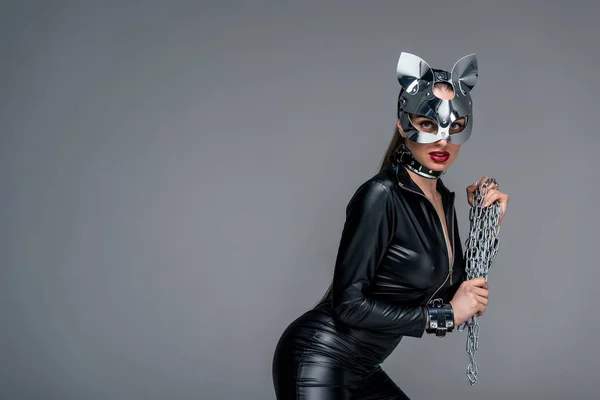 Kinky Frau in sexy Kostüm mit Kette in den Händen isoliert auf grau — Stockfoto