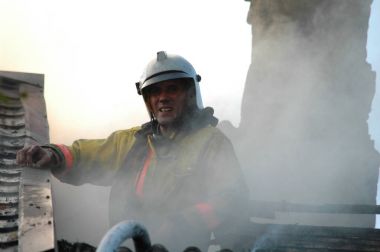 İtfaiyeci yanan bir eve çatıda özel bir form içinde