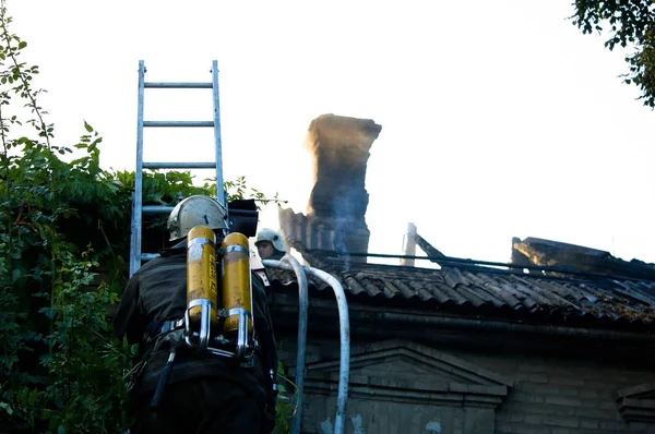 Пожарные в специальной форме на крыше горящего дома — стоковое фото