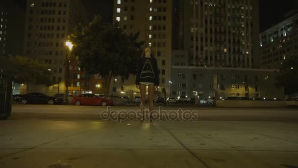 Girl staying on the downtown street and looking on a tall building. Girl stopped and looking up. Time Lapse night city on background — Stockvideo