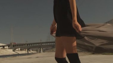 Güzel kız positing, dans, koşma, La nehrine yürüme sallayarak kumaş ile. Sanayi Bölgesi moda videoshoot.