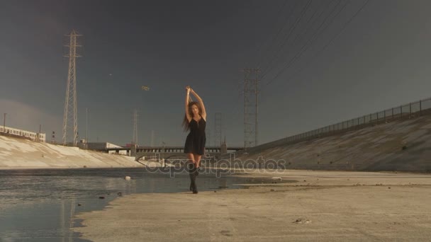 Gyönyörű lány a hullámzó szövet positing, tánc, futás, séta a folyó partján. Ipari terület divat videoshoot. — Stock videók