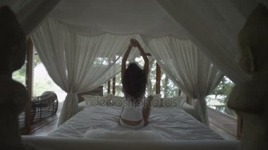 Uyuyan kız uyanır. Romantik yatak gölgelik altında. Ormanın içinde yatak odası. Kadın, esneme ve yatakta uyanmayı uzanır. Uyanır ve hızlı bir şekilde yataktan alır. Uyuya kalmış! Ağır çekim