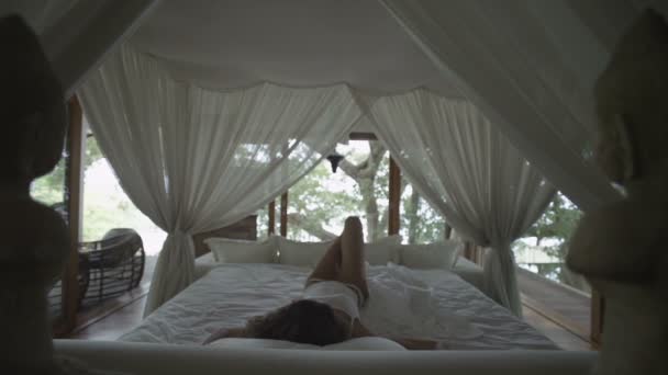 Спящая девушка просыпается. Романтическая кровать под навесом. Спальня в лесу. Женщина растягивается, зевает и просыпается в постели. Просыпается и быстро встает с кровати. Переспал! Slow Motion — стоковое видео
