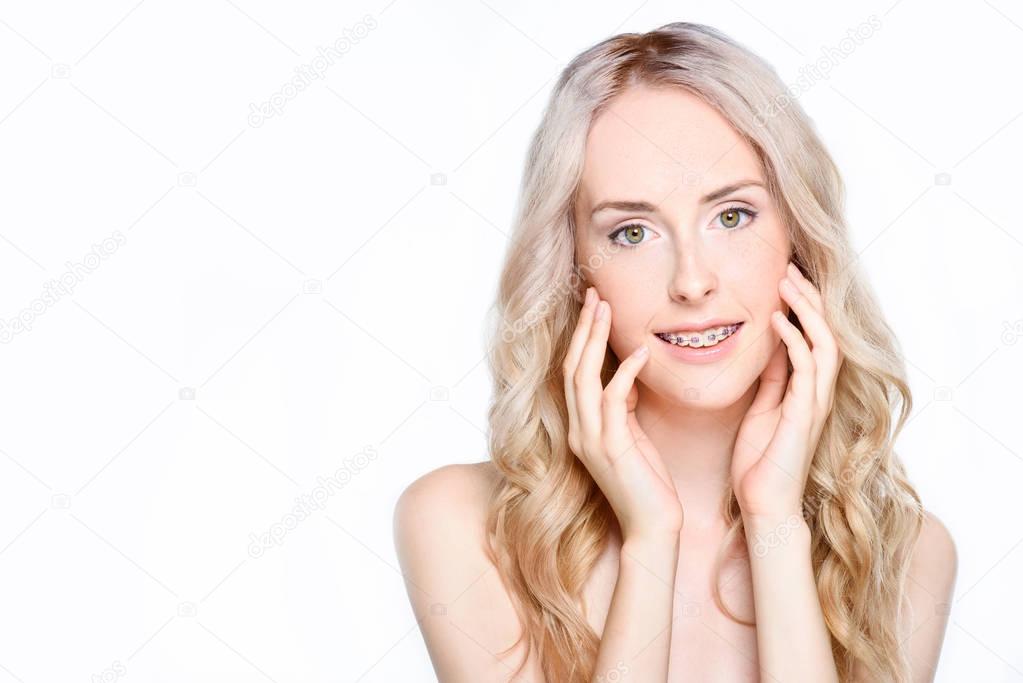 Woman with braces touching face