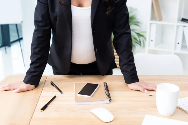 Έγκυος επιχειρηματίας που ακουμπά πάνω στο γραφείο — Δωρεάν Φωτογραφία