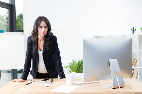 Gravida affärskvinna tittar på en dator — Stockfoto
