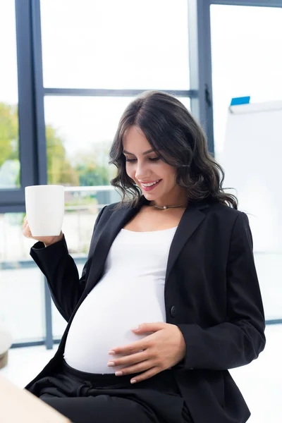 Těhotná moderátorka s šálkem horkého nápoje — Stock fotografie
