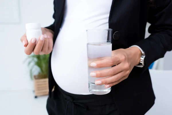 Schwangere Geschäftsfrau mit Pillen im Glas — Stockfoto