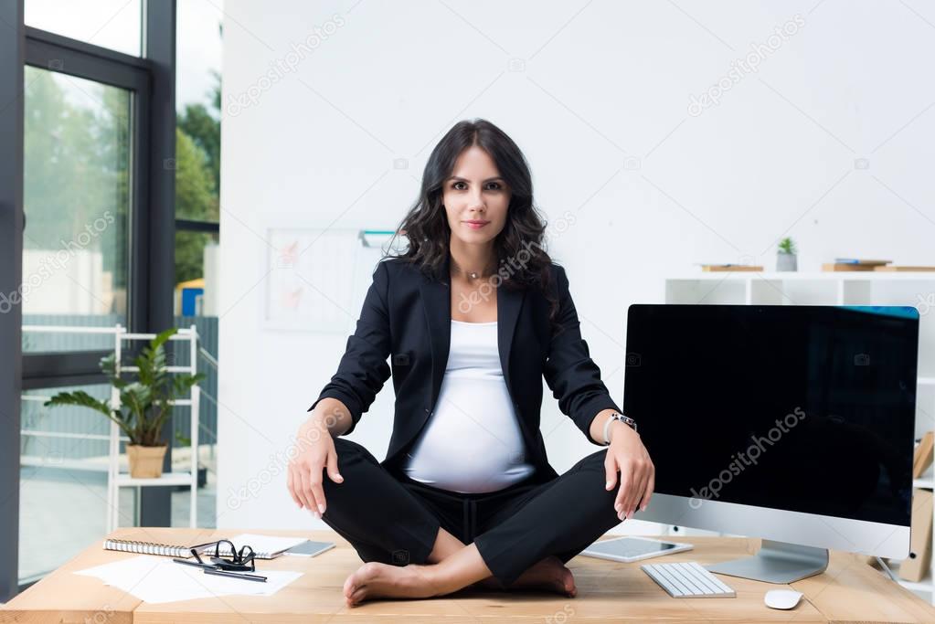 pregnant businesswoman on table in lotus pose