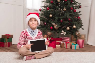 Noel Baba şapkalı tablet tutan çocuk