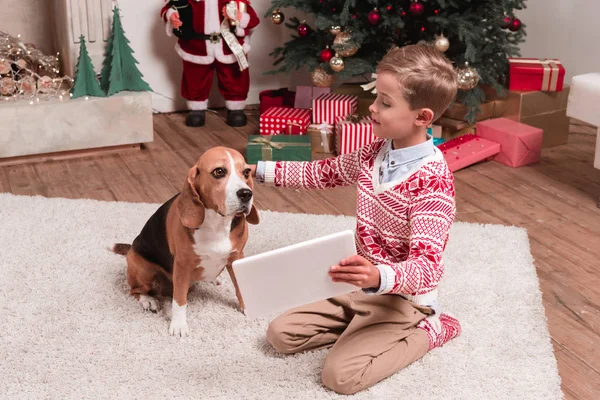 boy showing tablet to dog on christmas