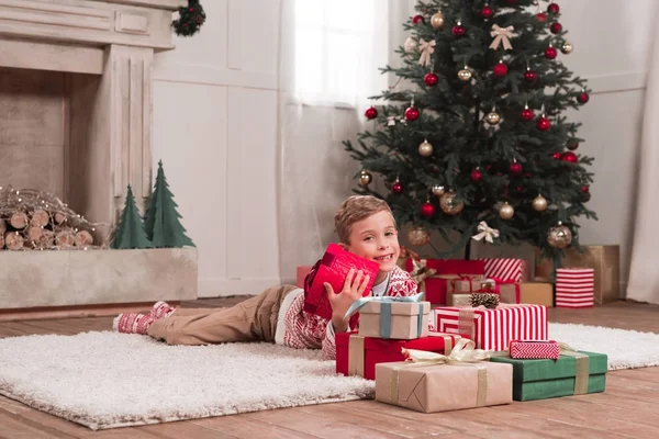 Boy laying on floor with christmas gifts — Stock Photo, Image